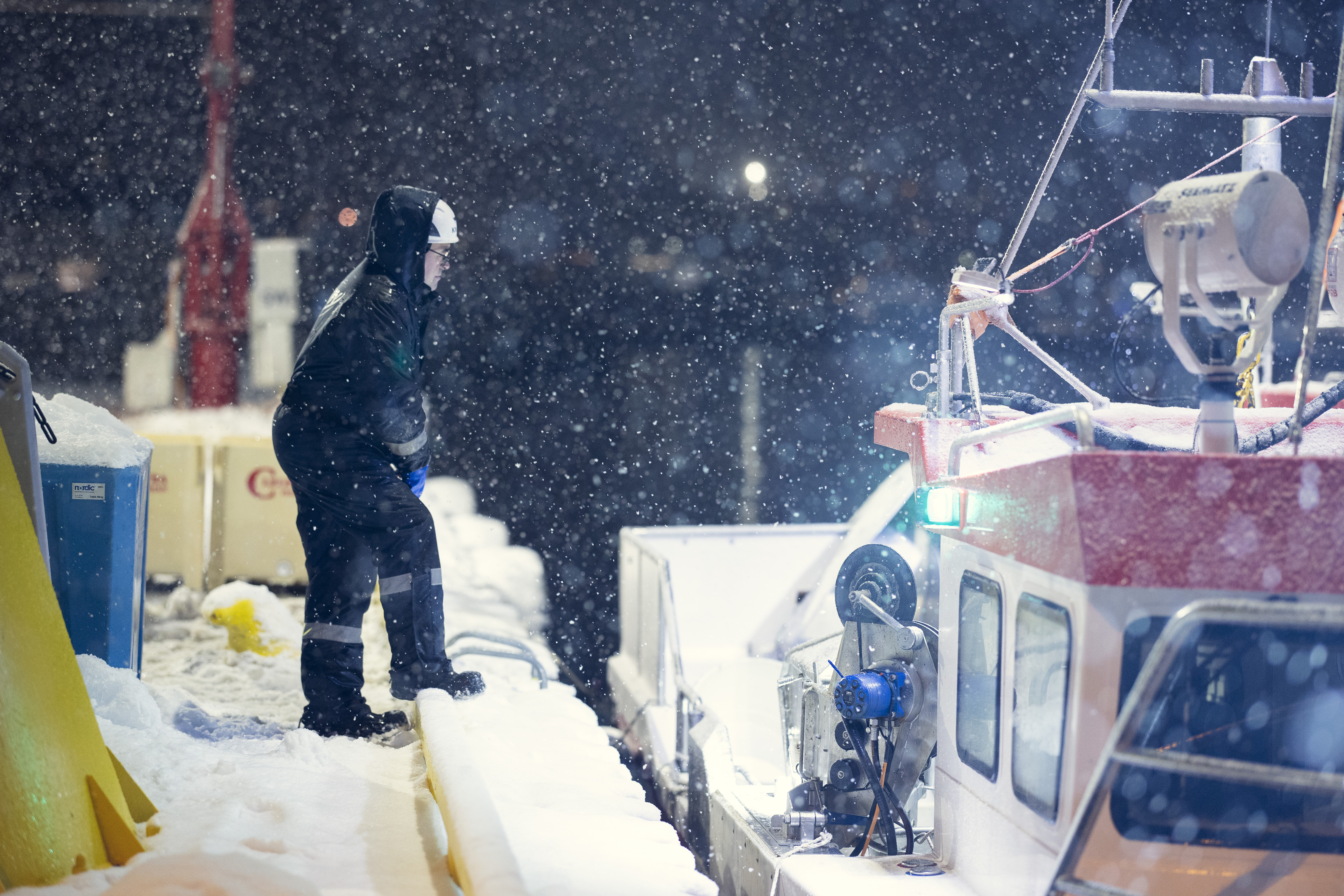 Worker in winter condition on quay next to fishin boat