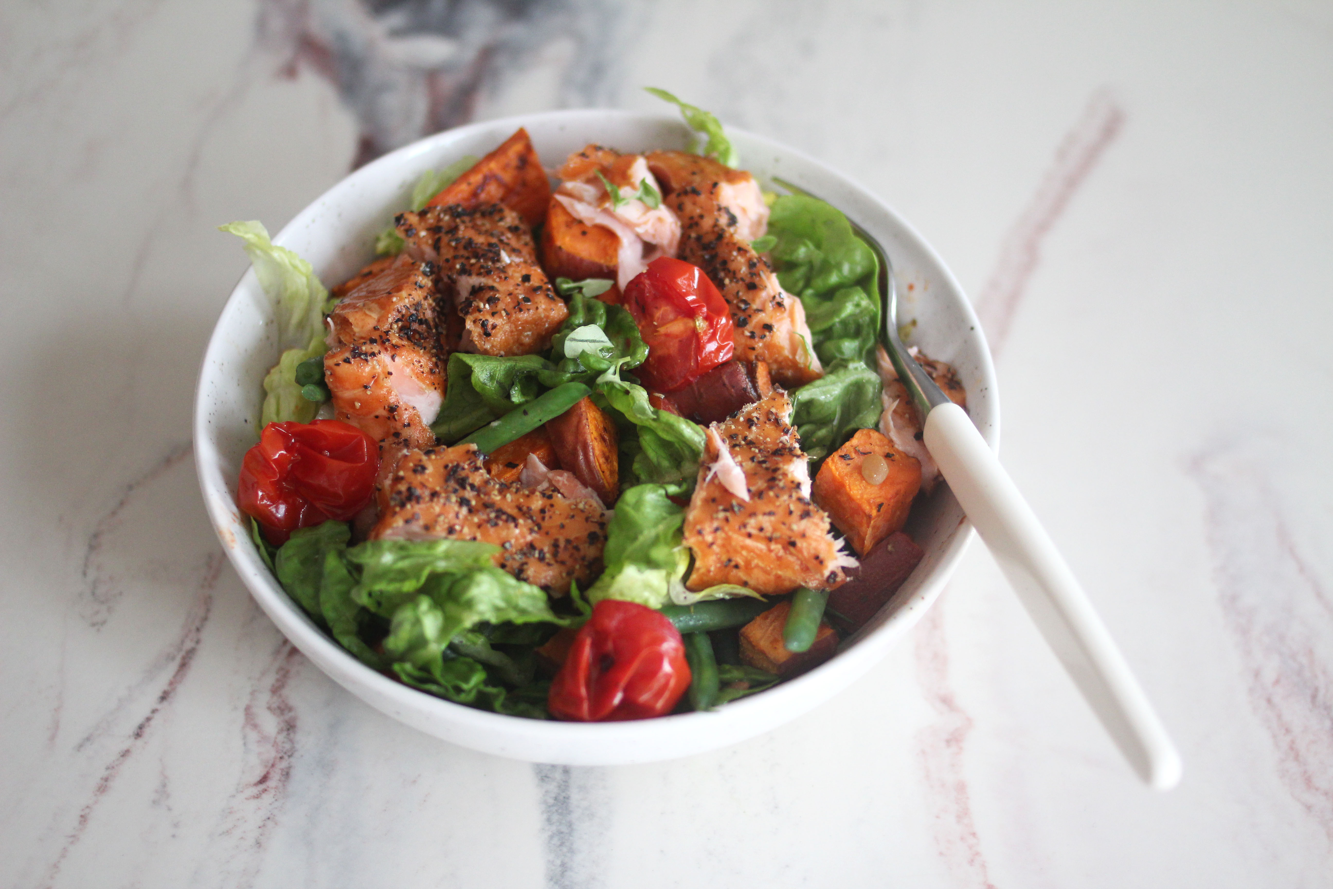 Fried salmon with salad and sesame seeds on a plate placed on a  nicely set table