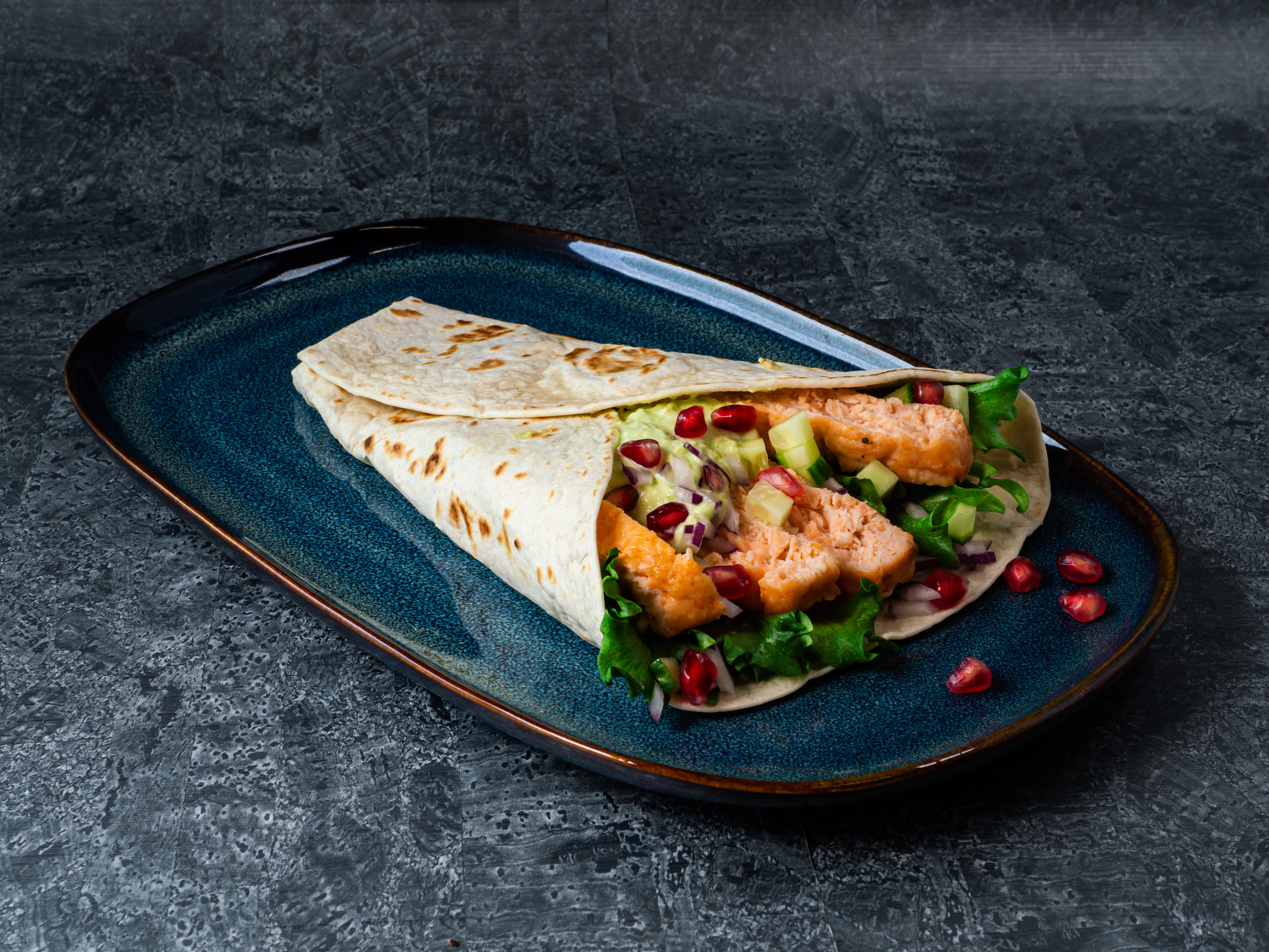 En tallerken med lakseburger i tortilla med wasabikrydret avokado- og rømmedressing 